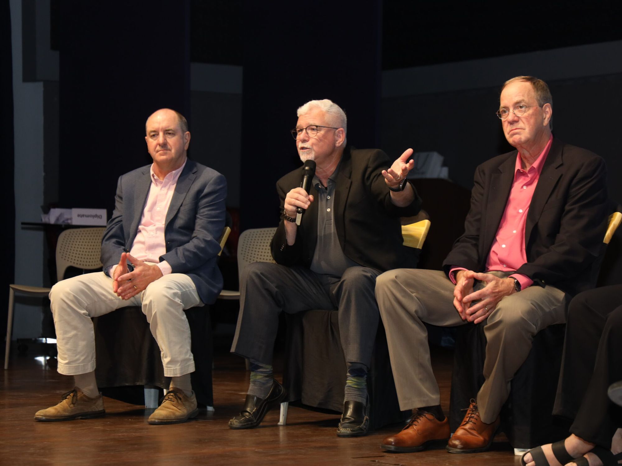 The three founders seated on stage, the one in the middle speaking into a microphone