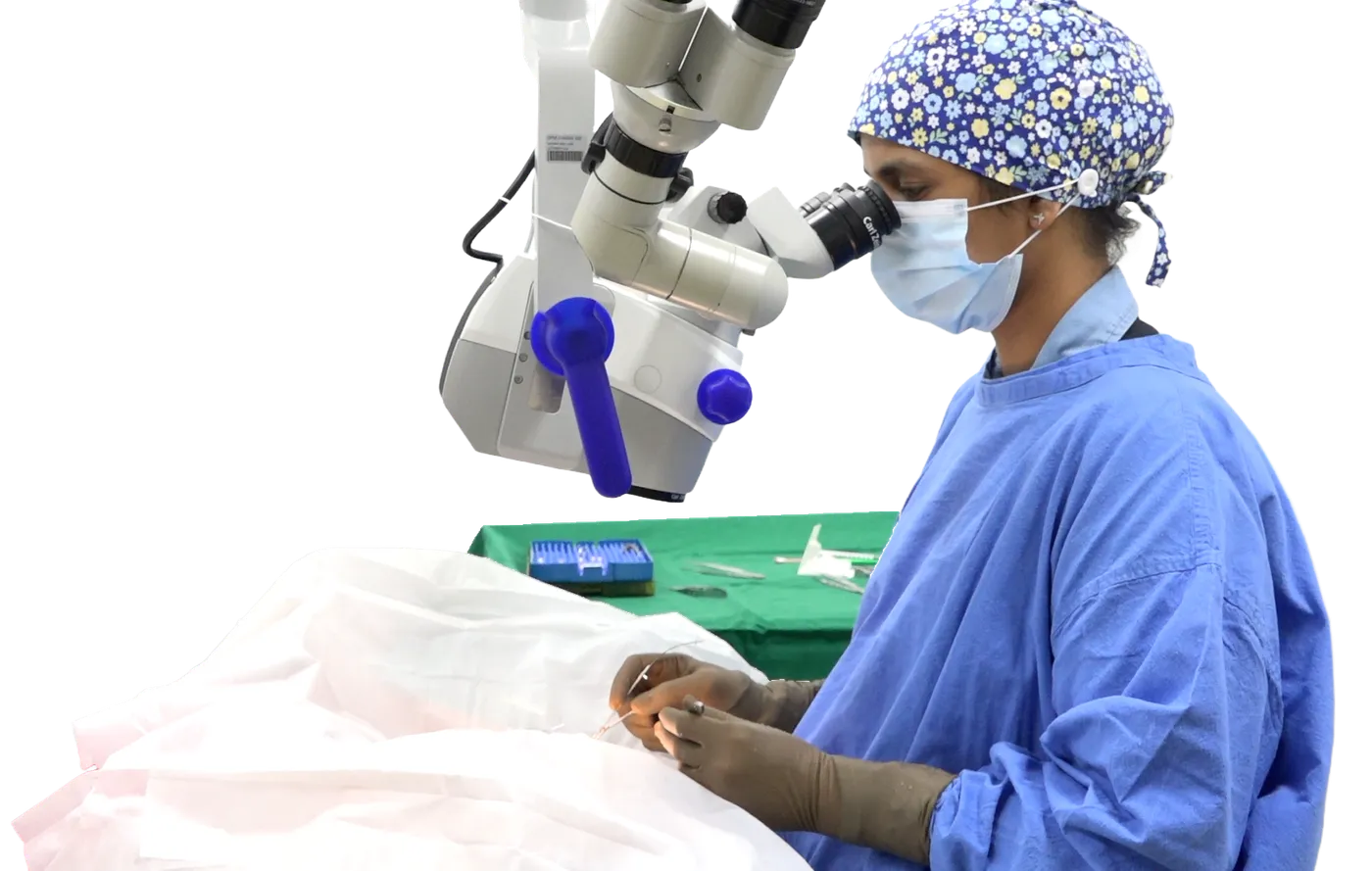 A surgeon in a scrub cap, mask and gown operating through an operating microscope